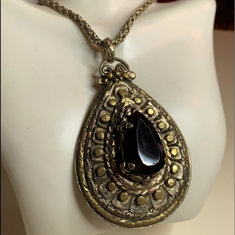 Garnet and metal teardrop pendant in a chain.